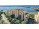 Aerial view of the yellow and pink condo building with water view of bay and a bridge in the background at 611 Riviera Dunes Way # 107, Palmetto, FL 34221