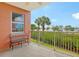 Covered balcony with metal bench overlooks lush greenery and water view beyond metal railing at 611 Riviera Dunes Way # 107, Palmetto, FL 34221