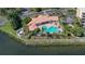 Aerial view of community pool and clubhouse overlooking water with palm trees and manicured landscaping at 611 Riviera Dunes Way # 107, Palmetto, FL 34221