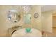 Chandelier and a round mirror and blue chairs around a white table at 611 Riviera Dunes Way # 107, Palmetto, FL 34221