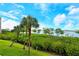 Picturesque water view with palm trees and lush green landscape under a blue sky with fluffy white clouds at 611 Riviera Dunes Way # 107, Palmetto, FL 34221