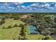 Scenic aerial view showcasing lush greenery, tennis courts, a clubhouse, and golf course in a residential area at 7278 Lismore Ct, Lakewood Ranch, FL 34202