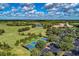 Aerial view of lush green golf course and surrounding community, with tennis courts, a clubhouse, and parking at 7278 Lismore Ct, Lakewood Ranch, FL 34202