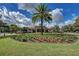 Community clubhouse with a lush garden and verdant lawn beneath a blue sky filled with puffy white clouds at 7278 Lismore Ct, Lakewood Ranch, FL 34202