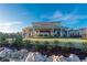 Expansive clubhouse exterior featuring a large covered patio, scenic landscaping, and lush greenery at 7278 Lismore Ct, Lakewood Ranch, FL 34202