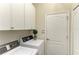Bright laundry room with a washer, dryer, overhead cabinets, and a door at 7278 Lismore Ct, Lakewood Ranch, FL 34202