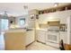 Well-lit kitchen featuring white cabinetry and appliances, adjacent to the living area at 850 S Tamiami Trl # 207, Sarasota, FL 34236