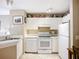 Bright kitchen featuring white cabinetry, appliances, and a view of the breakfast table at 850 S Tamiami Trl # 207, Sarasota, FL 34236