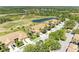 Aerial view showcases a golf course, pond, and residential properties surrounded by trees at 9121 Stone Harbour Loop, Bradenton, FL 34212
