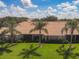 A back exterior view of the property showcasing a tile roof, landscaping and tropical palm trees at 9121 Stone Harbour Loop, Bradenton, FL 34212