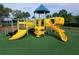 Vibrant yellow playground equipment on a green artificial turf with a slide and blue awning at 9121 Stone Harbour Loop, Bradenton, FL 34212