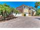 Mediterranean home exterior featuring a brick driveway, tropical landscaping, and a two-car garage at 9429 Discovery Ter # 102B, Bradenton, FL 34212