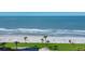 Beautiful Beach view of manicured landscaping, palm trees, white sand, and rolling waves at 1000 Longboat Club Rd # 604, Longboat Key, FL 34228
