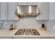 Close-up of a gas cooktop with stainless steel hood, set against a stylish backsplash at 10510 Giddens Pl, Palmetto, FL 34221