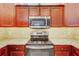 Kitchen features stainless steel microwave, range, granite countertops and wooden cabinets at 12091 Amica Loop, Venice, FL 34293