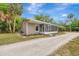 Cozy home with a screened-in porch and a gravel driveway surrounded by lush landscaping at 1240 Fox Creek Dr, Sarasota, FL 34240