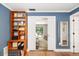 Hallway with blue walls, wooden floors, open bookcase, sliding pocket doors, and decorative mirror at 1434 Ladue Ln, Sarasota, FL 34231