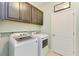 Laundry room featuring modern, front load washer and dryer with dark wood cabinets and shelf at 15612 Trinity Fall Way, Bradenton, FL 34212