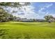 View of the manicured golf course and a putting green, surrounded by mature trees and beautiful landscaping at 2020 Calusa Lakes Blvd, Nokomis, FL 34275