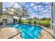 Screened-in pool area with brick paver decking, clear blue water, and landscaping around the screen enclosure at 2020 Calusa Lakes Blvd, Nokomis, FL 34275