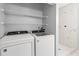 Bright laundry area with a washer, dryer, and shelving for optimal storage space, plus a white-tiled standing shower at 218 80Th N Ave, St Petersburg, FL 33702