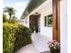 Close up of the front entry with a modern door, wood accents, and lush landscaping around the entryway at 2242 Sunnyside Ln, Sarasota, FL 34239