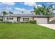 Charming home with a well-manicured lawn, mature trees, and an attached two-car garage at 2242 Sunnyside Ln, Sarasota, FL 34239