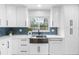 Modern kitchen featuring white cabinets, quartz counters, farmhouse sink, and a stylish blue herringbone backsplash at 2242 Sunnyside Ln, Sarasota, FL 34239