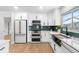 Bright kitchen showcasing white cabinetry, stainless steel appliances, herringbone backsplash, and hardwood floors at 2242 Sunnyside Ln, Sarasota, FL 34239