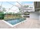 Sparkling swimming pool with screened enclosure and concrete surround at 2242 Sunnyside Ln, Sarasota, FL 34239