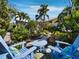 Serene backyard with lush greenery, stone pathway, and charming blue Adirondack chairs at 3322 Bayou Rd, Longboat Key, FL 34228