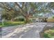 Charming single-story home featuring a beautifully landscaped front yard with mature trees and a brick-paved driveway at 3526 Austin St, Sarasota, FL 34231