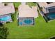 Aerial view of a single-story home featuring a screened pool with an umbrella, surrounded by green lawn at 3606 Garden Lakes Clenet, Bradenton, FL 34203