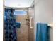 Well-lit shower with tile walls, a shower head, built in shelves, a shower curtain and a grab bar at 3606 Garden Lakes Clenet, Bradenton, FL 34203