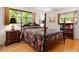 Bedroom with hardwood floors, a four-poster bed, two windows, and a wooden bookshelf at 3626 Medford Ln # 1537, Sarasota, FL 34232