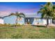 Charming home with lush lawn, palm trees, and quaint front porch under a colorful sky at 4908 Arlington Rd, Palmetto, FL 34221