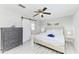 Bright bedroom with a bed, ceiling fan, dresser, and sliding barn door to the attached bathroom at 507 Shore Dr, Largo, FL 33771