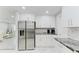 Bright, modern kitchen with stainless steel refrigerator, granite countertops and white cabinets at 507 Shore Dr, Largo, FL 33771