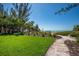 Landscaped backyard with lush green lawn and stone path leading to beach access and beautiful ocean views at 5125 Gulf Of Mexico Dr # 4, Longboat Key, FL 34228