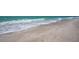 Ocean waves gently rolling onto a sandy beach on a bright, sunny day with beautiful blue-green water at 5125 Gulf Of Mexico Dr # 4, Longboat Key, FL 34228