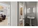Tastefully-designed powder room with pedestal sink, decorative mirror and storage cabinet above the toilet at 5442 Kent Rd, Venice, FL 34293