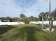 Green backyard features lush grass, a white fence, and mature palm trees at 5578 Thyer St, North Port, FL 34288