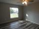 Bright bedroom featuring wood-look floors, ceiling fan, and a street view through the window at 5578 Thyer St, North Port, FL 34288