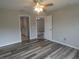 Bright bedroom with wood-look floors, ceiling fan, and multiple doorways to other rooms at 5578 Thyer St, North Port, FL 34288