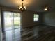 Bright living room with hardwood floors, ceiling fan, chandelier, sliding doors, and backyard view at 5578 Thyer St, North Port, FL 34288