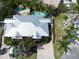 Aerial view of a home with a modern metal roof, two pools, lush landscaping, and a paver driveway at 5608 Holmes Blvd, Holmes Beach, FL 34217