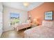 Inviting bedroom featuring two twin beds, bright coral walls, and a ceiling fan at 5608 Holmes Blvd, Holmes Beach, FL 34217