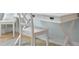 Close-up of a well-lit white wooden desk with a chair on a tile floor at 5608 Holmes Blvd, Holmes Beach, FL 34217