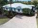 Attractive home featuring mature landscaping, light blue siding, impact windows, and a beautiful paver driveway at 5608 Holmes Blvd, Holmes Beach, FL 34217