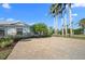 Charming home featuring a paver driveway, lush landscaping, and swaying palm trees at 5608 Holmes Blvd, Holmes Beach, FL 34217
